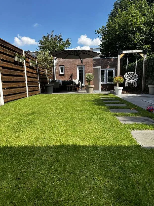 Verzorgde achtertuin met gazon en houten schutting